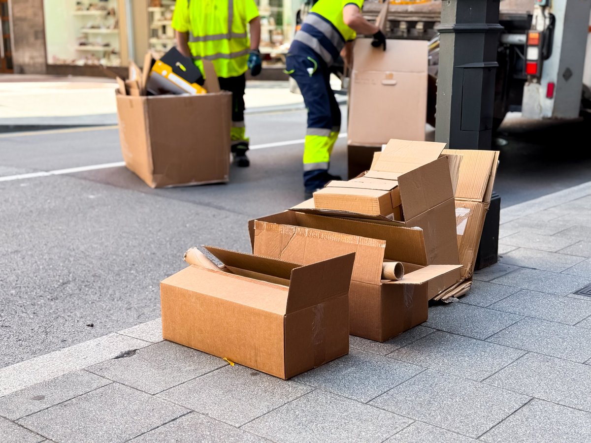 Workers disposing of cardboard boxes on city street