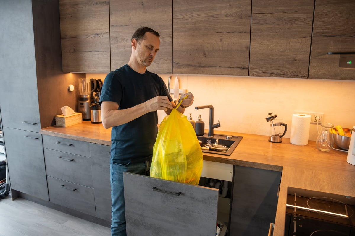 Man throwing garbage into a bin in a modern kitchen